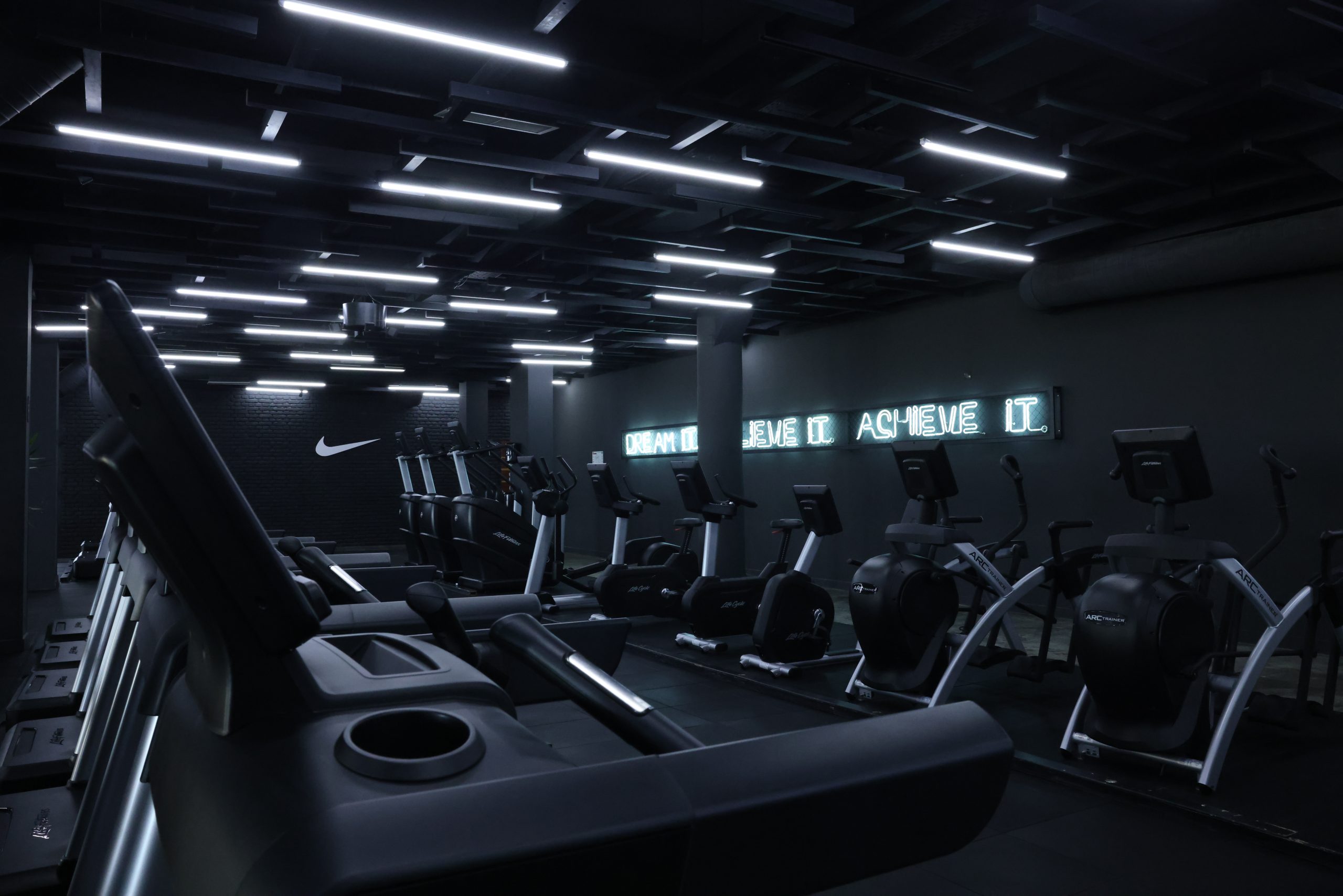 Salle de sport Passage Fitness éclairée par des rampes LED au plafond, avec ses appareils de cardio
