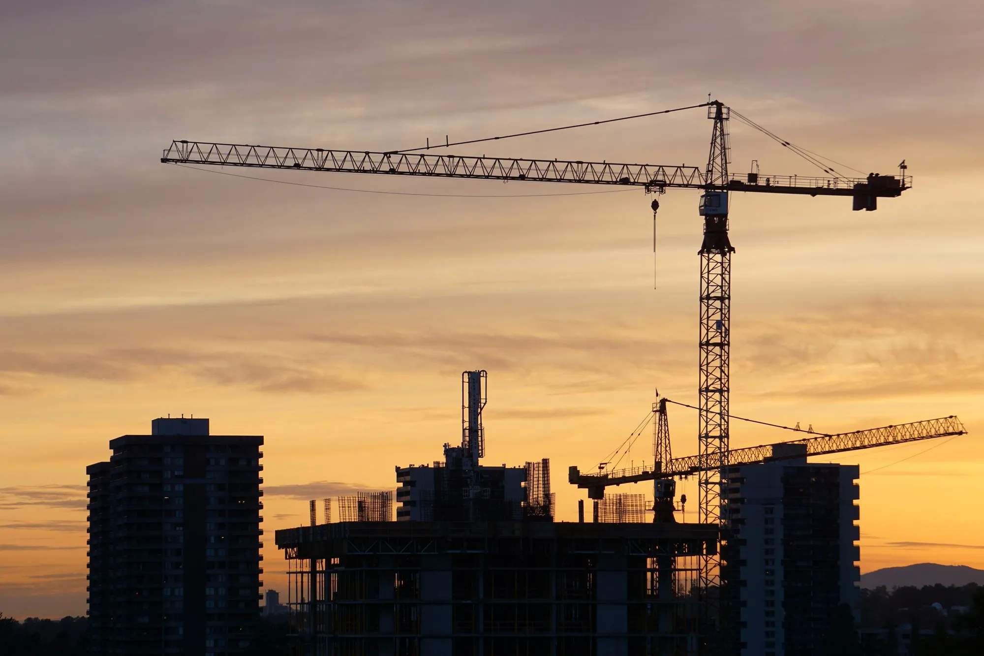 Grues et immeubles en construction au coucher du soleil